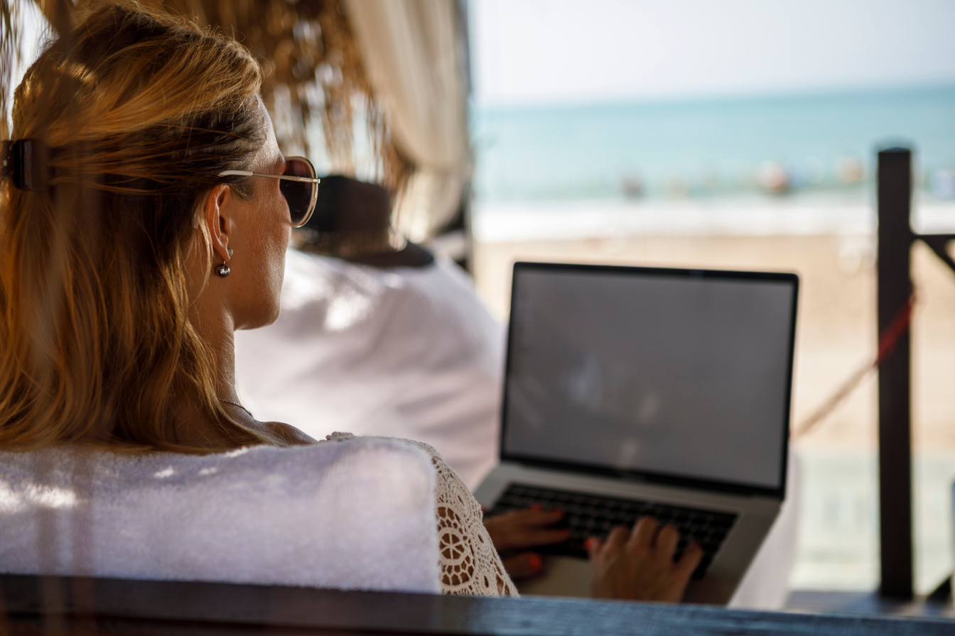 Woman at beach working on laptop